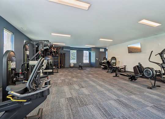 A spacious gym with a variety of equipment including treadmills, elliptical machines, and weight machines.