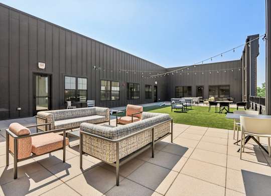 A modern outdoor seating area with a black building in the background.