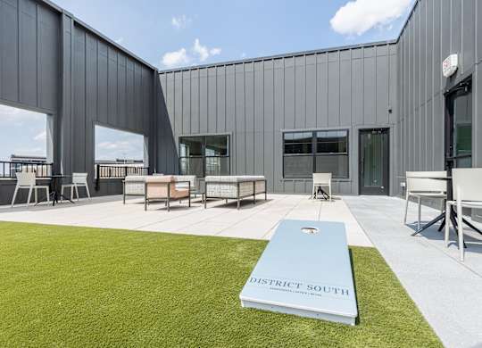 A modern building with a grassy area in front and a book titled District South on the grass.