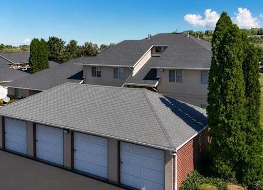 A house with a grey roof and a red flower bed in front.