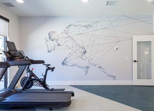 A treadmill is in a room with a wall mural of a world map.