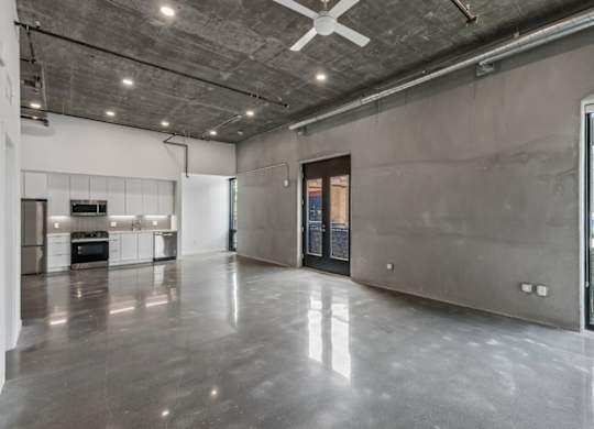 A spacious, empty room with a ceiling fan and a view of the outdoors through a glass door.
