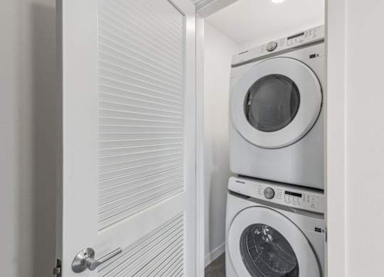 A white door is open to a laundry room with two washing machines.