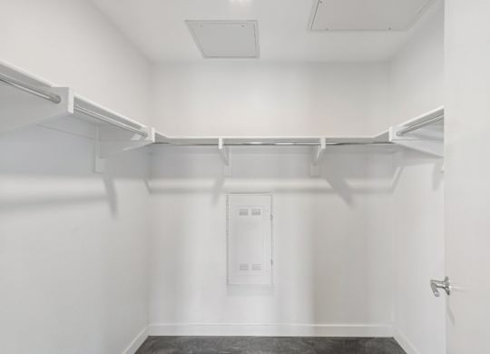 A white closet with a door and a shelf.