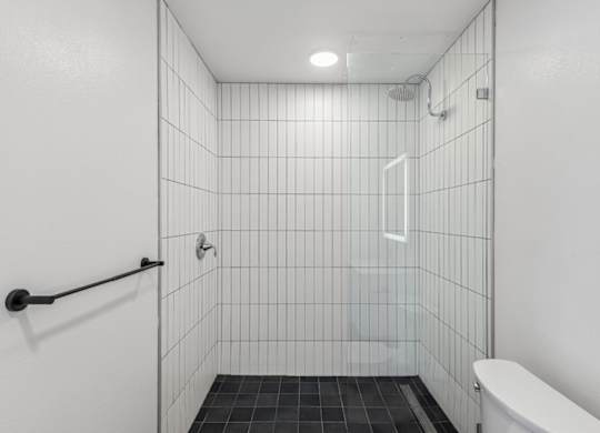 A white tiled bathroom with a toilet and a shower.