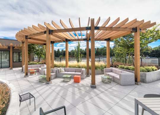 A wooden pergola shades a seating area in a courtyard.