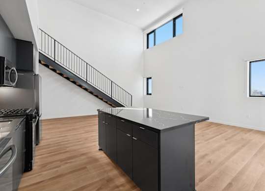A modern kitchen with a wooden floor and a stainless steel refrigerator.