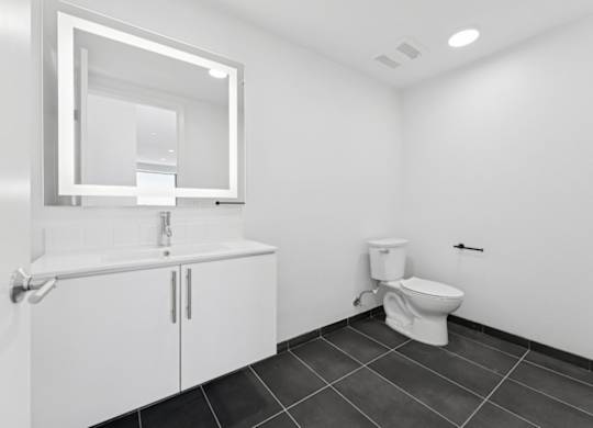 A white bathroom with a toilet, sink, and mirror.