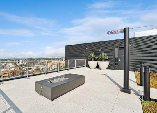 A modern outdoor patio area with a fire pit and a view of the city.