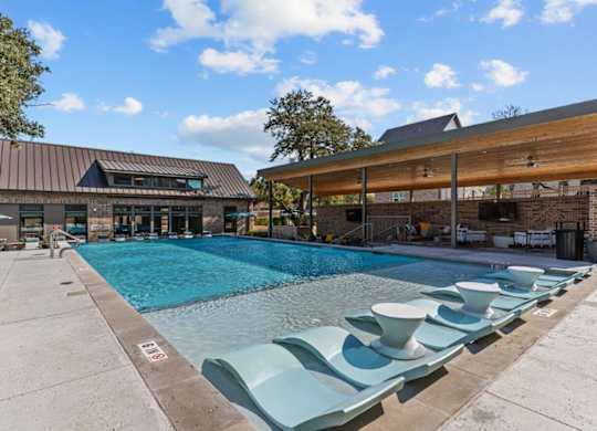 A pool with lounge chairs and a building in the background.