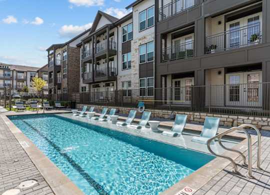 A pool with chairs around it in front of a building.