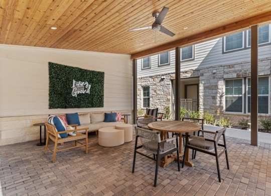 A patio with a wooden table and chairs and a green wall with the word