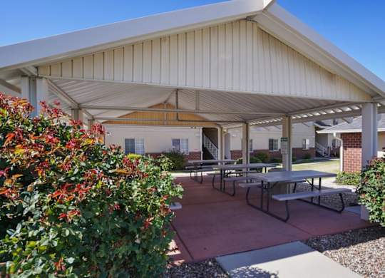A covered patio area with tables and benches.