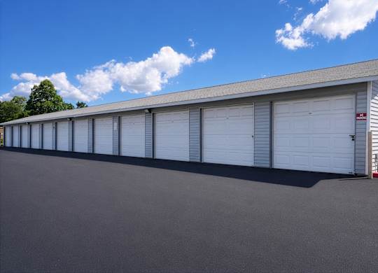 A long building with a grey roof and white garage doors.