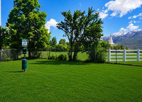 A green grassy area with a sign and a fence.
