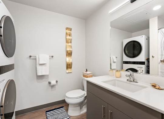 A modern bathroom with a toilet, sink, mirror, and towel rack.