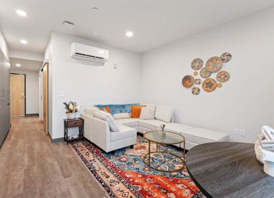 A modern living room with a white couch and a rug on the floor.
