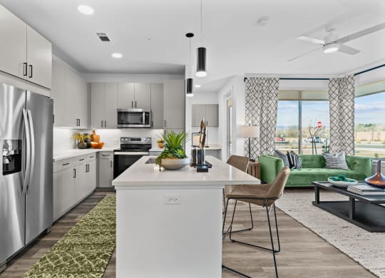 an open kitchen and living room with a stainless steel refrigerator