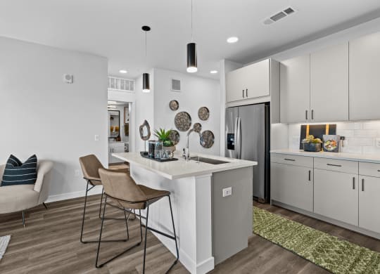 a kitchen with white cabinets and a white island with two stools
