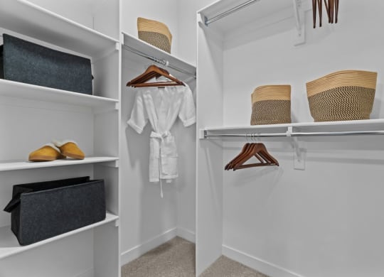 a walk in closet with white walls and shelves and a rack with hats and shoes