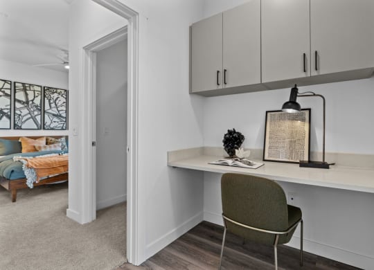 a small desk in a room with a door to a bedroom