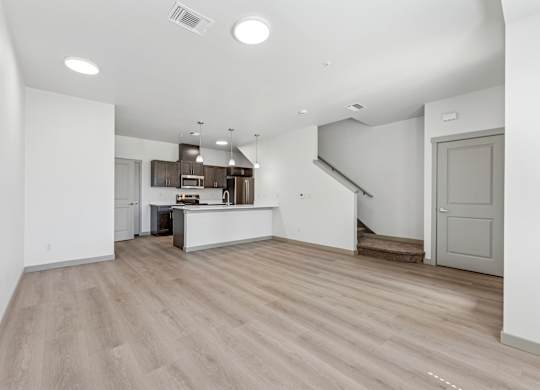A spacious kitchen with a bar area and a staircase in the background.