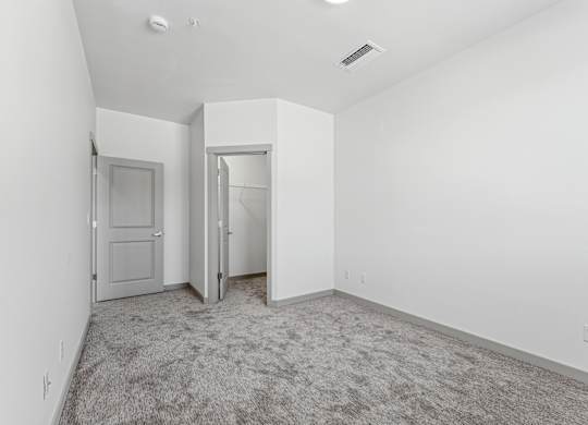 A room with a carpeted floor and two doors.