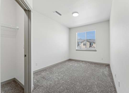 A room with a carpeted floor and a window showing a building outside.