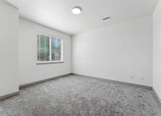 A room with a window and carpeted floor.