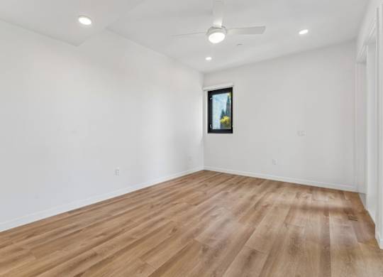 A room with wooden flooring and a ceiling fan.