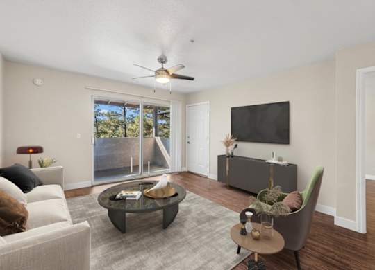 A living room with a white couch, a coffee table, a chair, and a flat screen TV mounted on the wall.