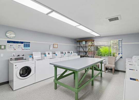 A laundry room with a table, chairs, and washing machines.