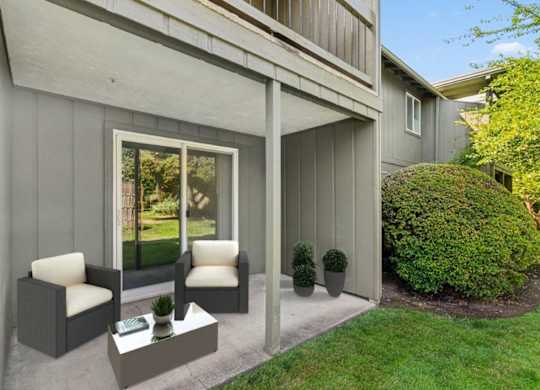 A grey house with a white chair and table outside.