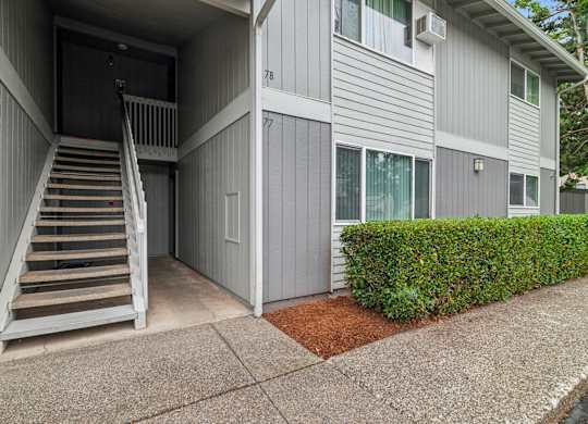 A grey building with a staircase leading to a door.