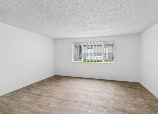 A room with a window and wooden flooring.