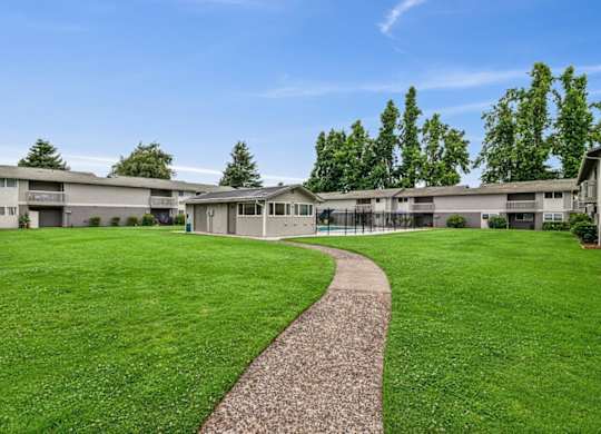 A grassy area with a concrete walkway leading to a building.