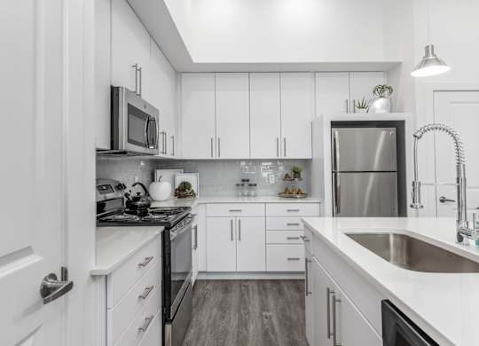 A modern kitchen with white cabinets and stainless steel appliances.