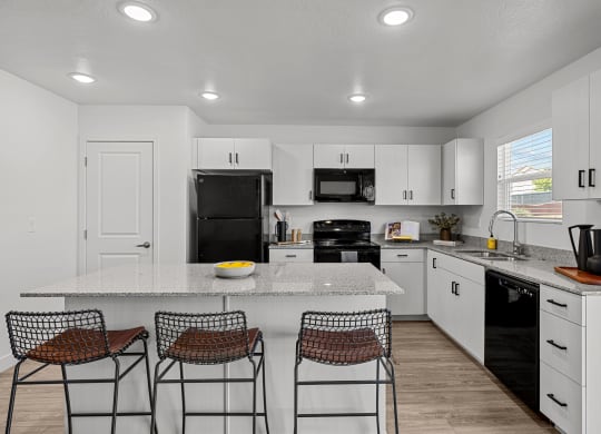 a kitchen with white cabinets and a counter top with three stools