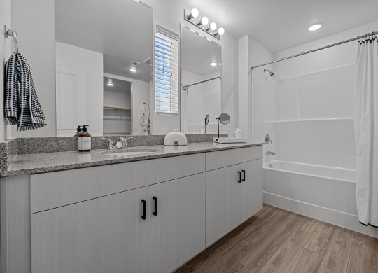 a bathroom with white cabinets and a large mirror and a shower