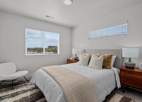 a bedroom with a large bed and two windows