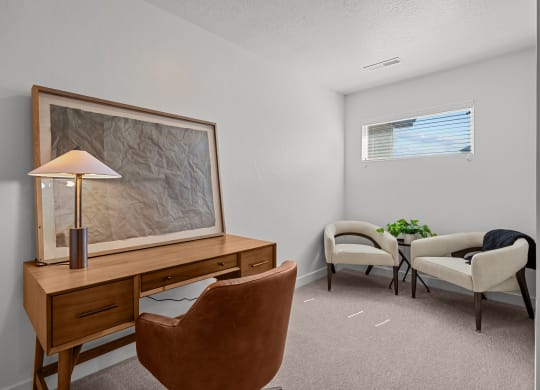 the living room has two chairs and a desk with a lamp and a table with