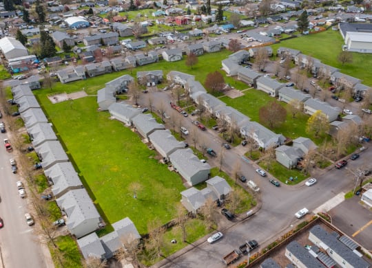an aerial view of a neighborhood with green grass and cars parked on the street
