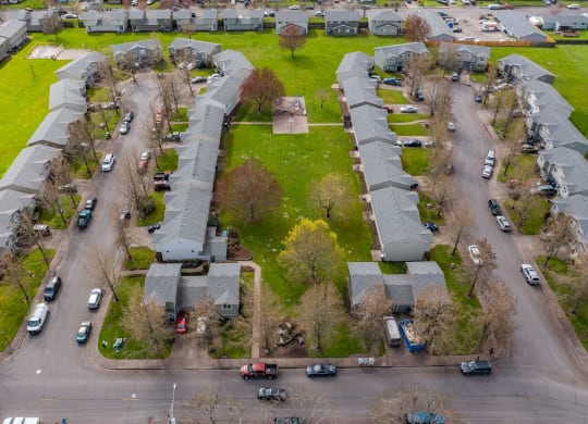 an aerial view of a neighborhood with green grass and cars parked on the street