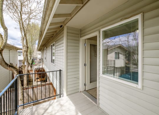 a front porch with a black railing and a white house in the background