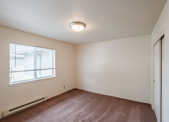 an empty bedroom with a large window and a closet