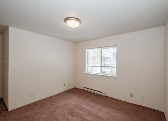 a bedroom with a large window and a carpeted floor
