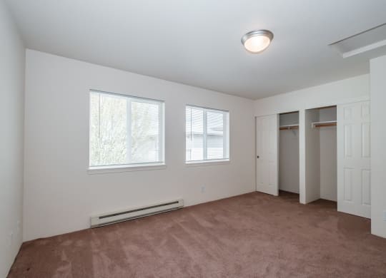 a bedroom with a carpeted floor and three windows