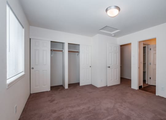 a bedroom with a carpeted floor and three closets