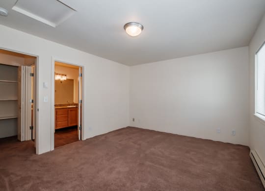 a bedroom with a carpeted floor and a door leading to a bathroom