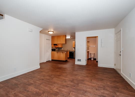 a living room with a hardwood floor and a kitchen in the background